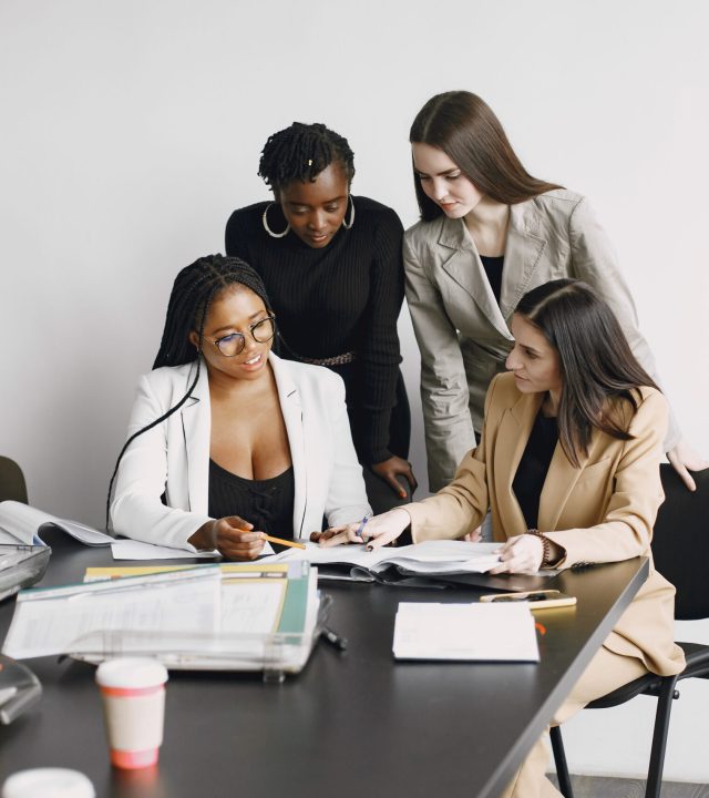 Multiracial office workers girls working together sitting at desk. Discussing business project